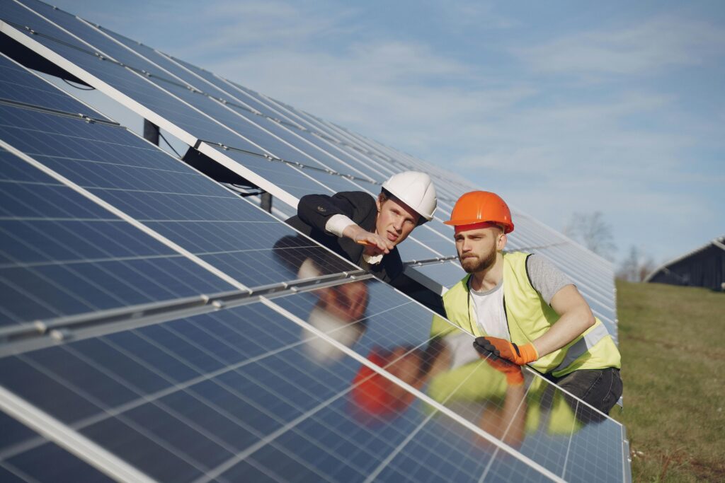 The Maintenance Standard: Off-Grid System Maintenance for Your Fortress Concentrated male coworkers in hardhats working at solar energy station and discussing technical aspects of panels